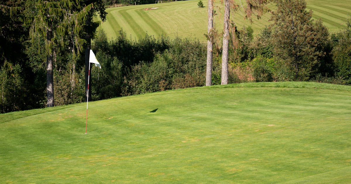 A vibrant green golf course fairway with flagstick