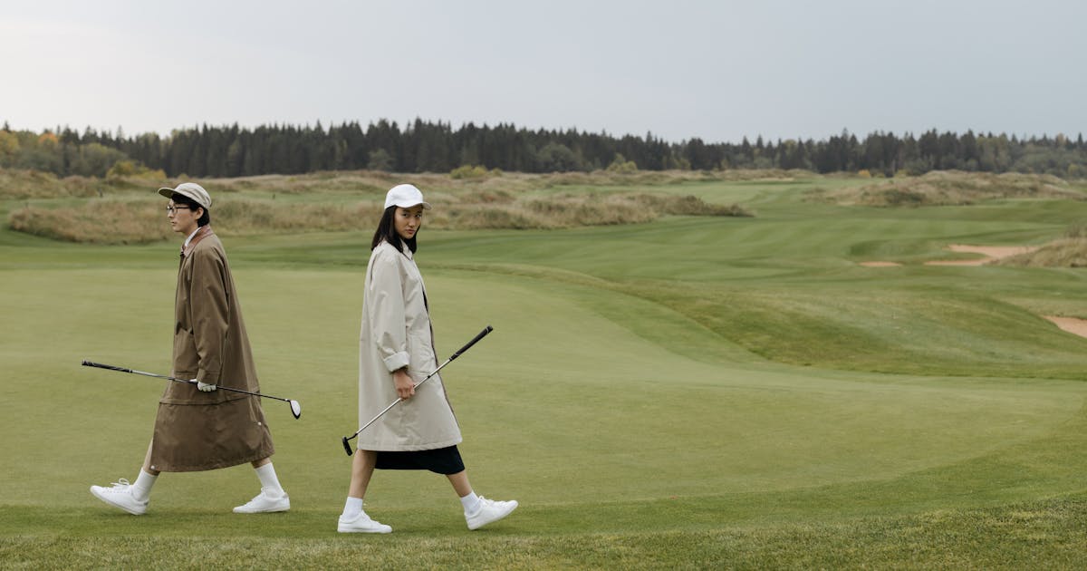 Two golfers walking across a lush, open golf course