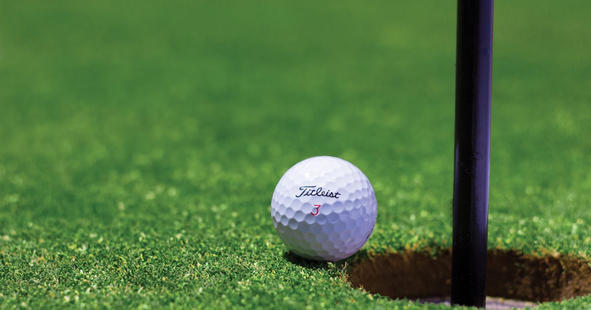 A golf ball near the hole on a vibrant putting green